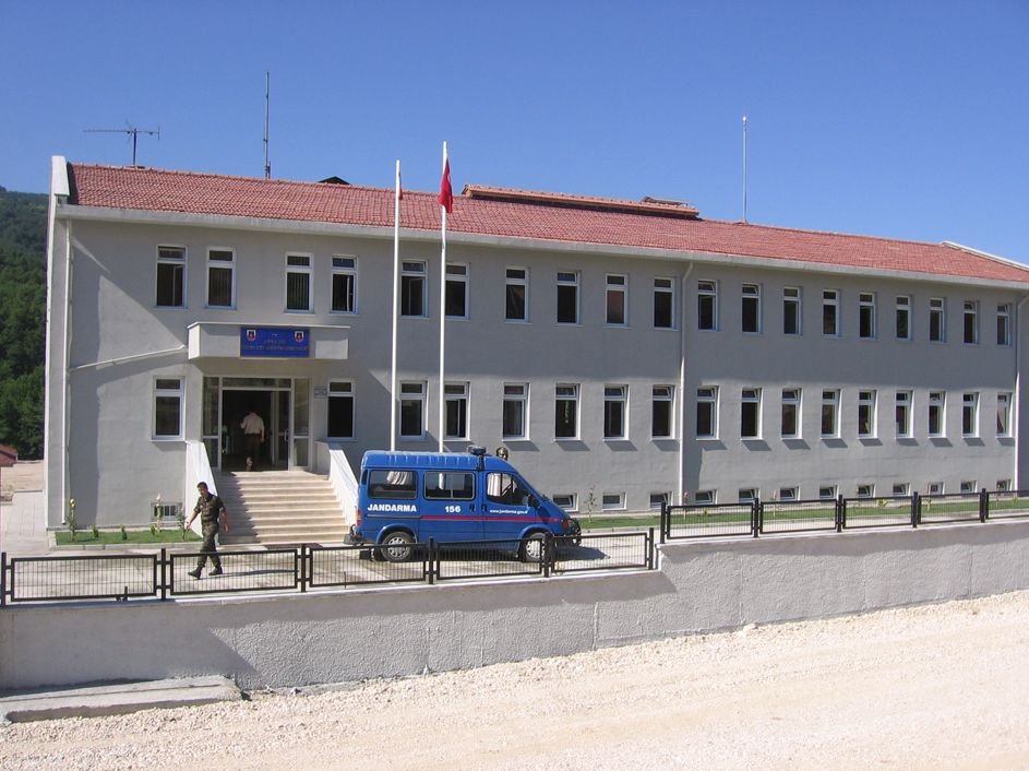 Yığılca Jandarma Komutanlığı binası: kiremit çatılı, iki katlı beyaz yapı, önünde bayrak direği ve jandarma aracı.