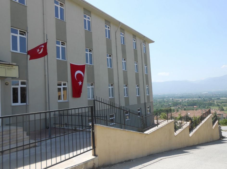 Düzce Halk Sağlığı Laboratuvarı binası: üç katlı açık renkli yapı, cephesinde iki Türk bayrağı, arkasında Düzce ovası.